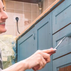 Eine Frau beim Lackieren der Küchenfronten in blau
