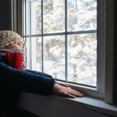 Kind schaut im Winter aus Fenster